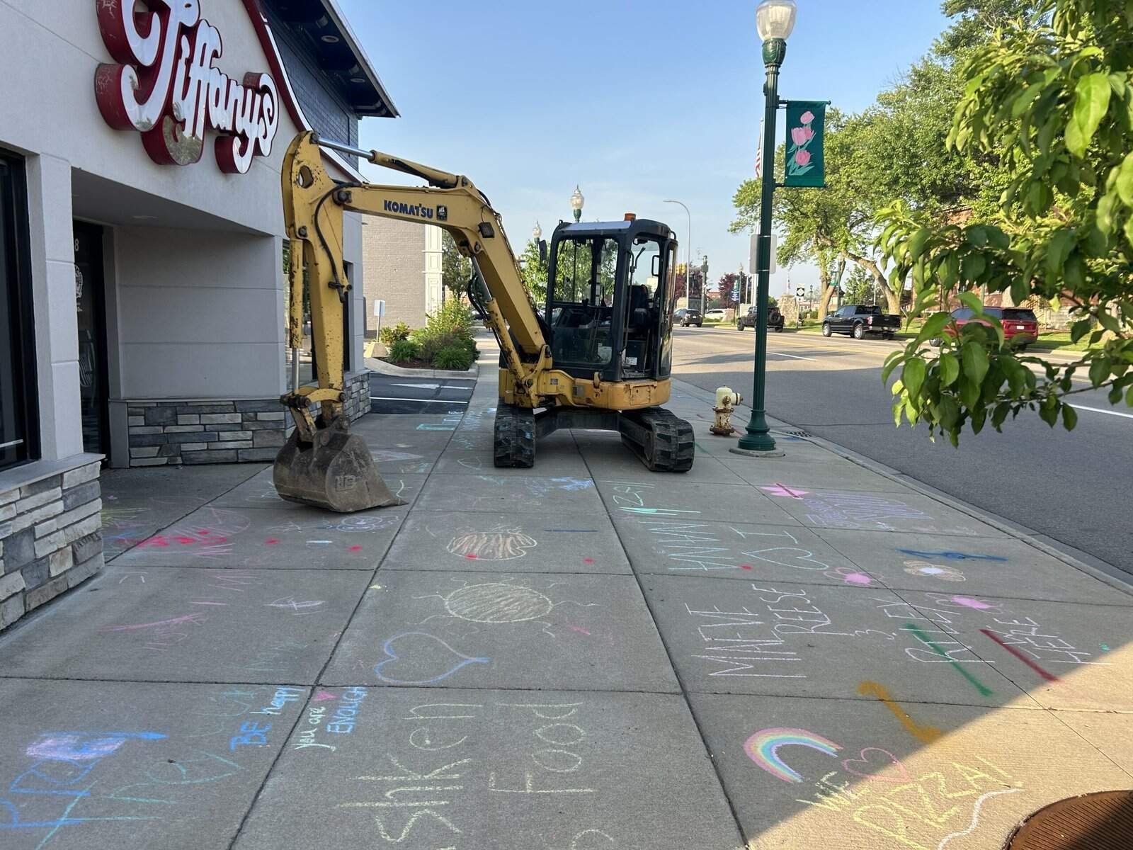 Thompson Trenchless and Hydro Jetting team checks pipes on a sidewalk by a restaurant with chalk drawings nearby.