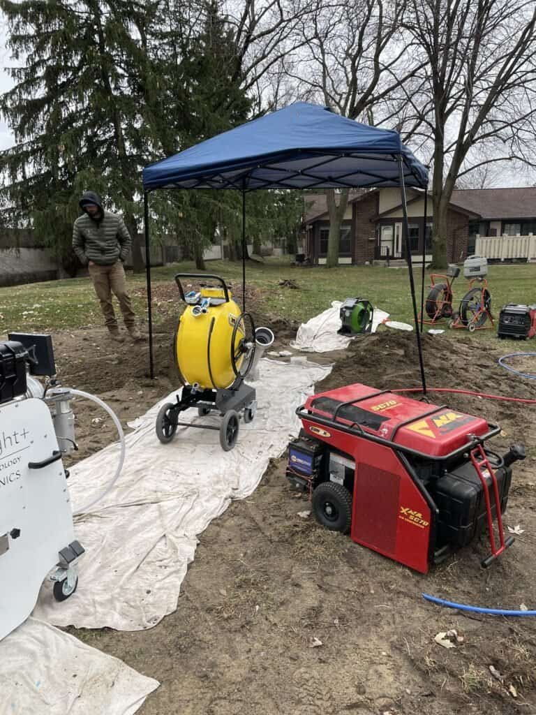 Thompson Trenchless and Hydro Jetting team prepares equipment outdoors to help clean drains for local homes in cool weather.