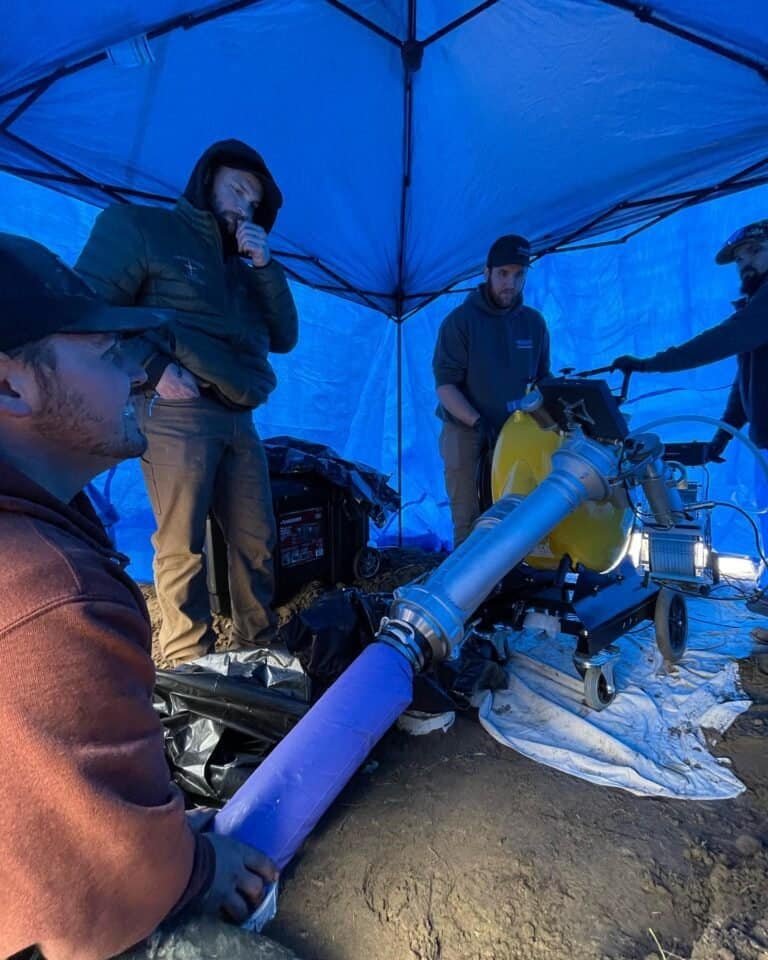 Thompson Trenchless and Hydro Jetting crew works together, using equipment to fix or inspect underground pipes outdoors.