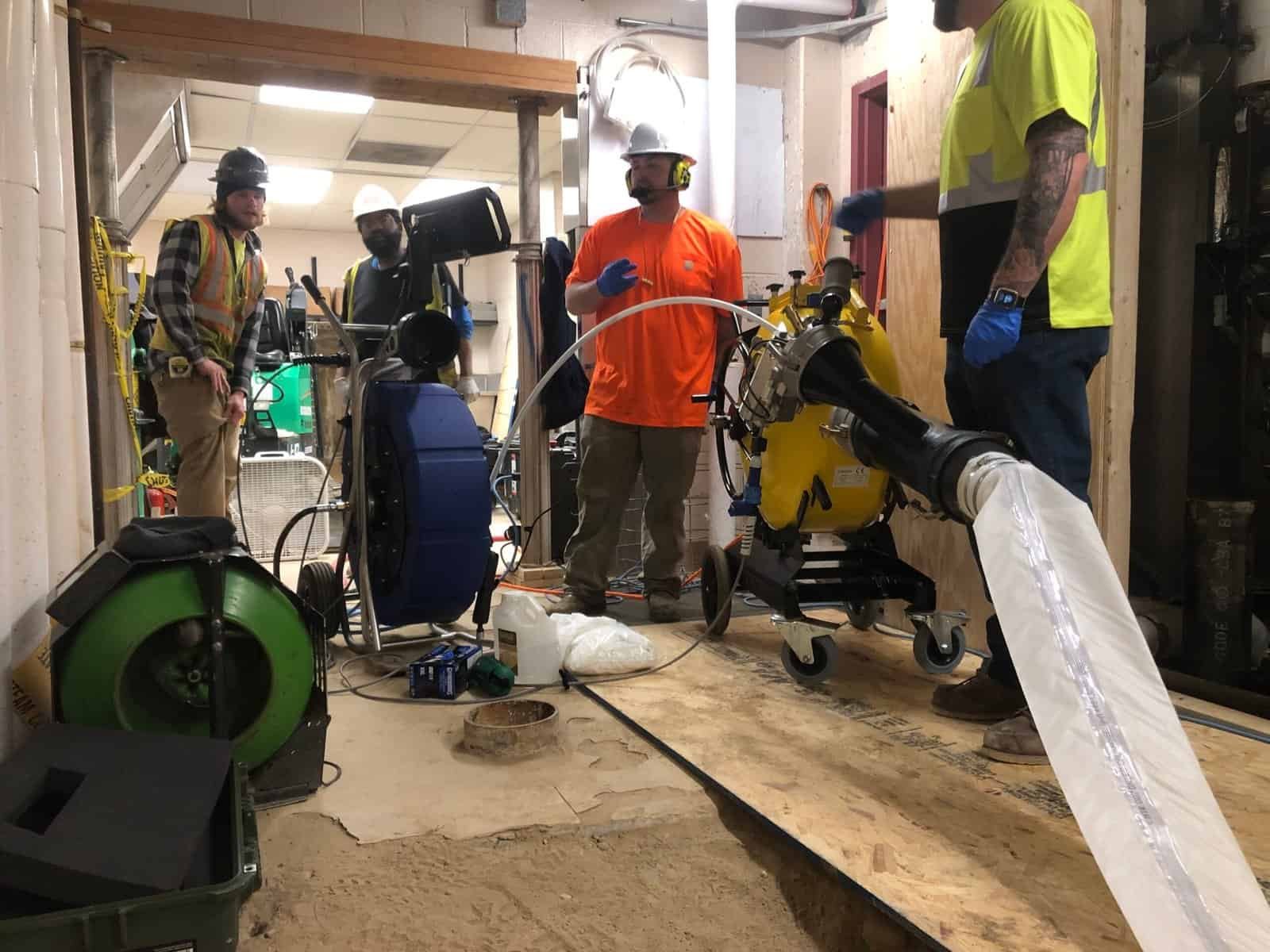 Thompson Trenchless and Hydro Jetting crew repairs pipes safely in a building under renovation, using special tools and equipment.
