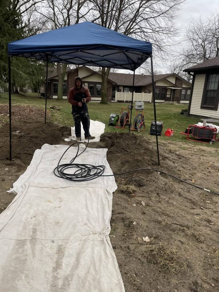 Thompson Trenchless and Hydro Jetting team prepares to fix underground pipes in a neighborhood on a cloudy day.