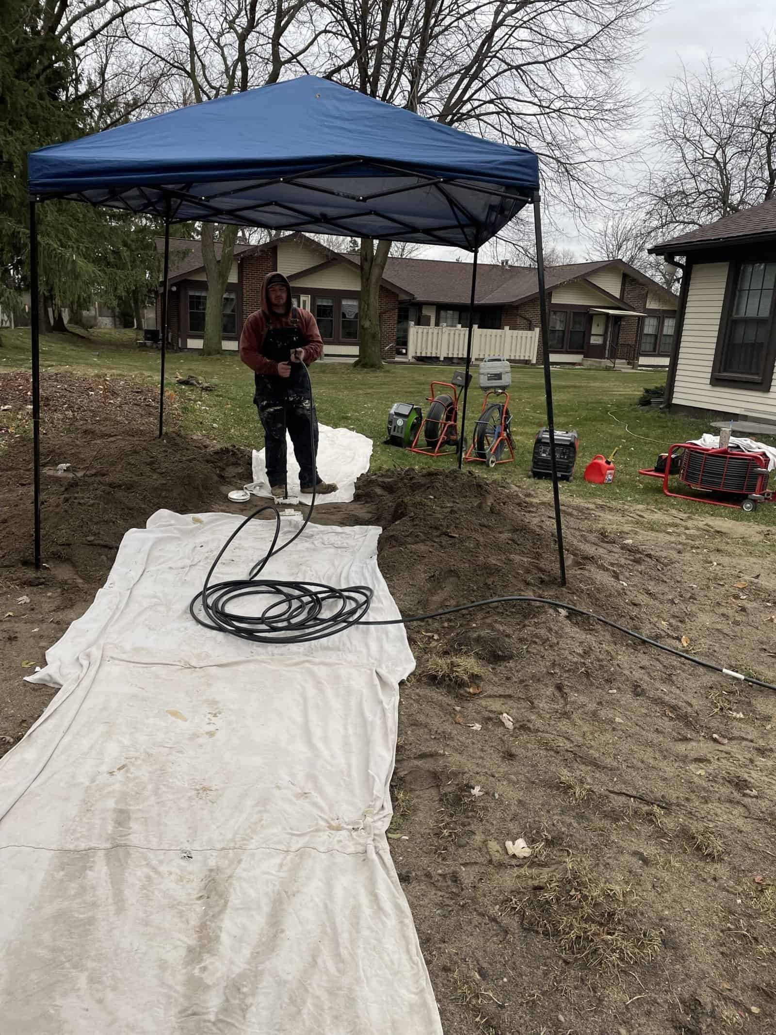 Thompson Trenchless and Hydro Jetting team prepares to fix underground pipes in a neighborhood on a cloudy day.