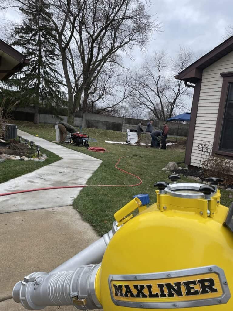Thompson Trenchless and Hydro Jetting works on pipe repair outside a house with equipment and a repair machine.