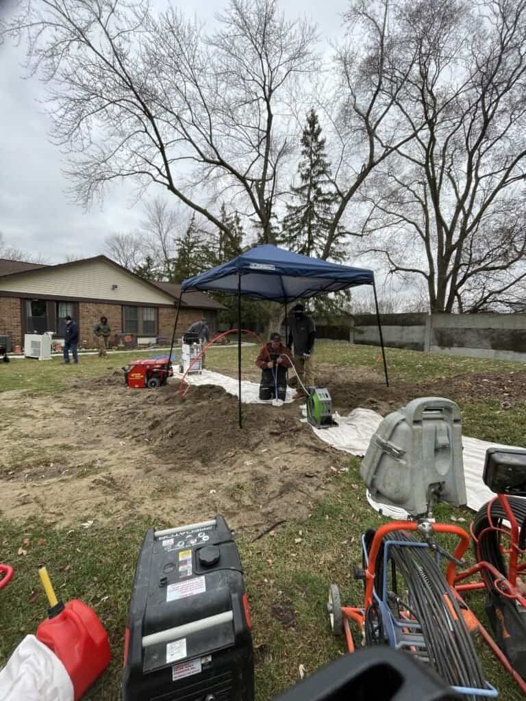 Thompson Trenchless and Hydro Jetting works on sewer line repair in a yard, showing tools and equipment in use.