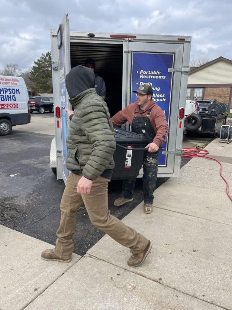 Thompson Trenchless and Hydro Jetting workers prepare equipment for restroom and pipe repair at a job site.