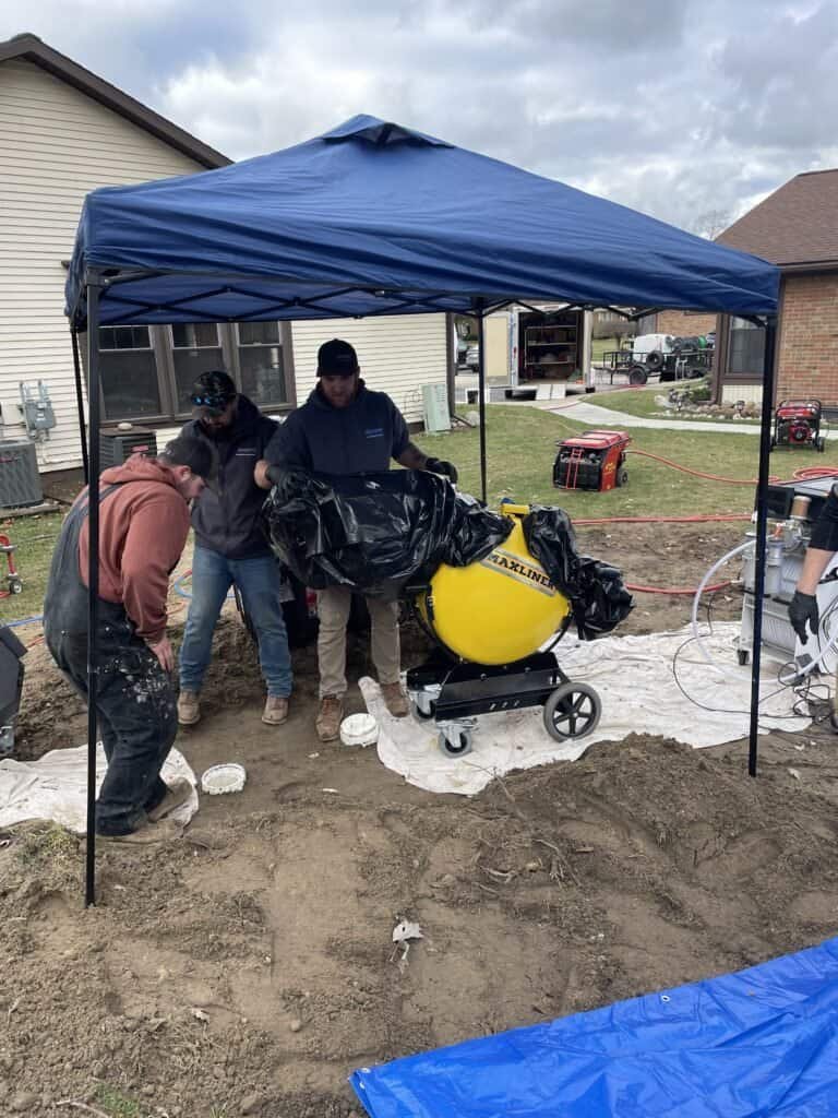 Thompson Trenchless and Hydro Jetting team prepares for pipe or drain work outside a house using their tools and equipment.