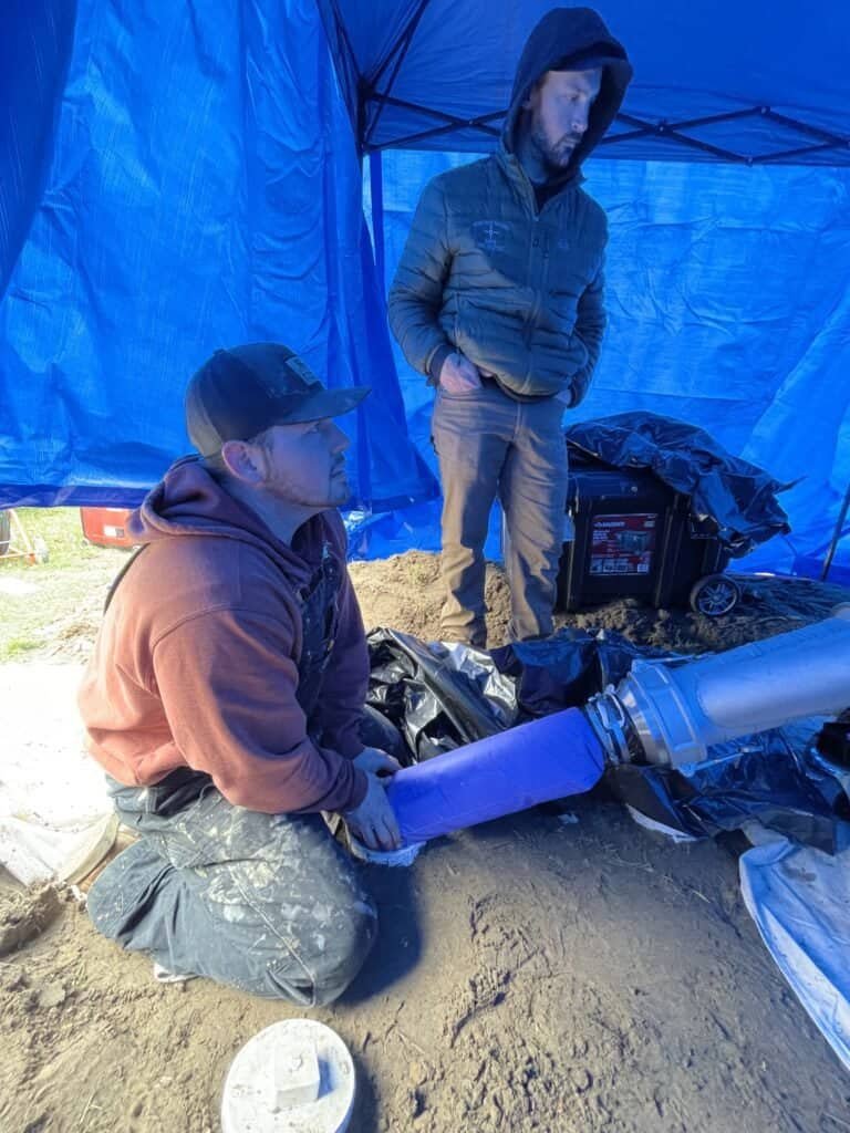 Thompson Trenchless and Hydro Jetting workers prepare pipes outdoors, getting ready for a pipe inspection job.