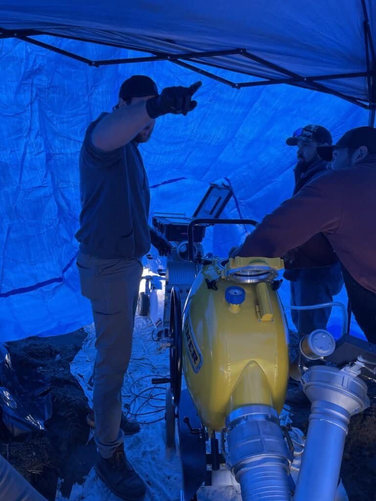 Thompson Trenchless and Hydro Jetting workers team up to fix sewer lines, showing teamwork and careful problem solving.