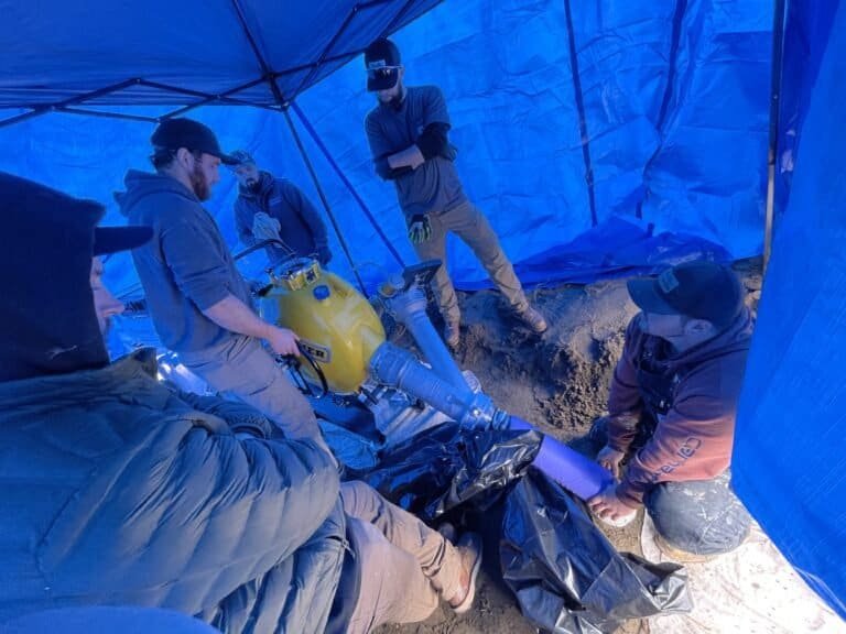 Thompson Trenchless and Hydro Jetting team repairs sewer lines together with special tools, showing teamwork and expertise.