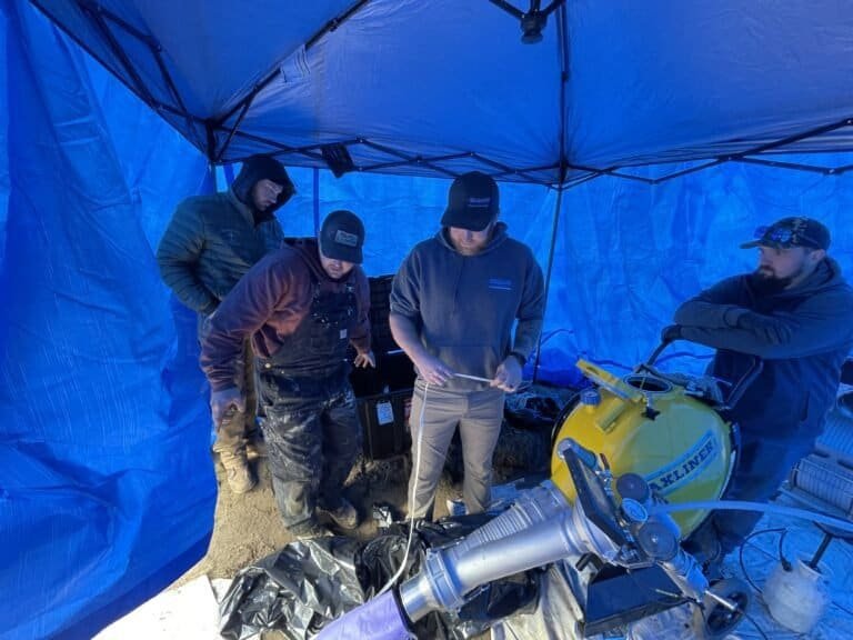 Thompson Trenchless and Hydro Jetting team works together on a sewer repair project, checking plans and equipment.