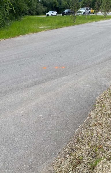 Thompson Trenchless and Hydro Jetting repairs sewer lines near a road while cars are parked alongside the work site.