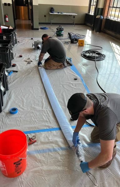 Thompson Trenchless and Hydro Jetting team repairs a pipe indoors using tools for quick, professional pipe solutions.