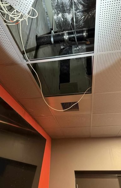 Thompson Trenchless and Hydro Jetting repairs pipes above ceiling panels, showing the work area for fixes in buildings.