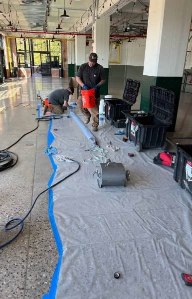 Thompson Trenchless and Hydro Jetting workers team up indoors to fix pipes, using special tools for the repair job.