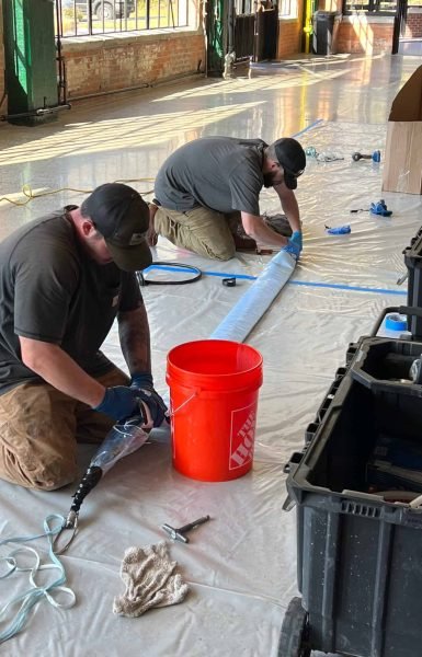 Thompson Trenchless and Hydro Jetting workers carefully repair sewer lines in a bright, clean workspace.