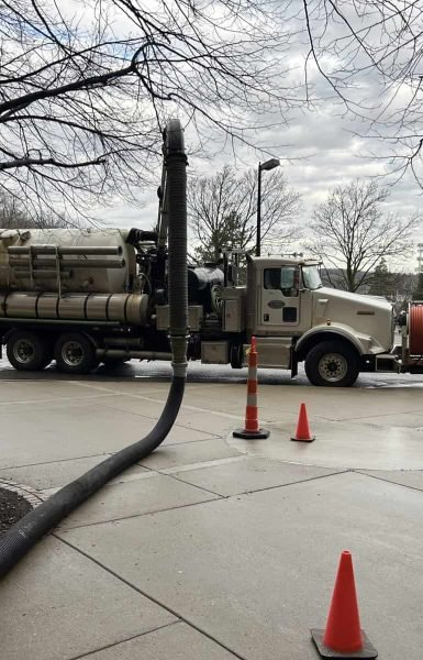 Thompson Trenchless and Hydro Jetting crew safely works with their truck on a rainy day, keeping the area clear for service.