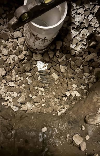 Thompson Trenchless and Hydro Jetting shows pipe parts ready for a plumber to inspect in a rocky, outdoor setting.