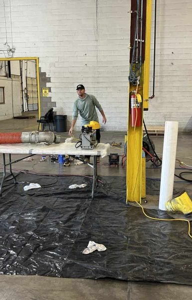 A worker at Thompson Trenchless and Hydro Jetting prepares pipe inspection equipment in a warehouse workspace.