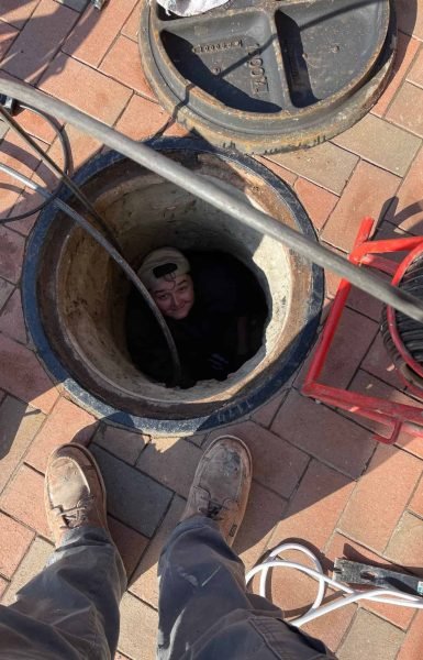 A Thompson Trenchless and Hydro Jetting worker checks a sewer line, showing how their team safely repairs underground pipes.