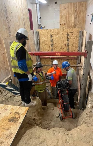 Thompson Trenchless and Hydro Jetting crew fixes sewer lines indoors while showing teamwork and confidence.