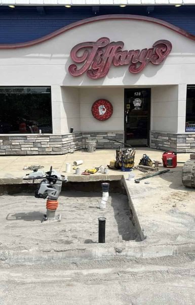 Thompson Trenchless and Hydro Jetting is inspecting or cleaning pipes outside a business in an active work area.